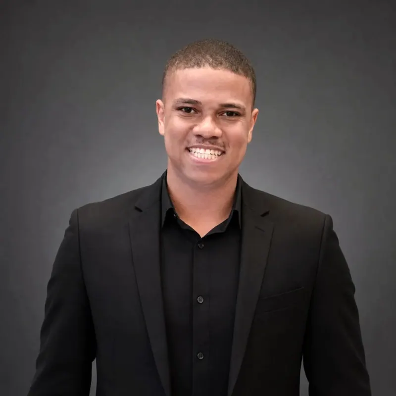 Contador de paletó preto, sorrindo, fundo cinza escuro